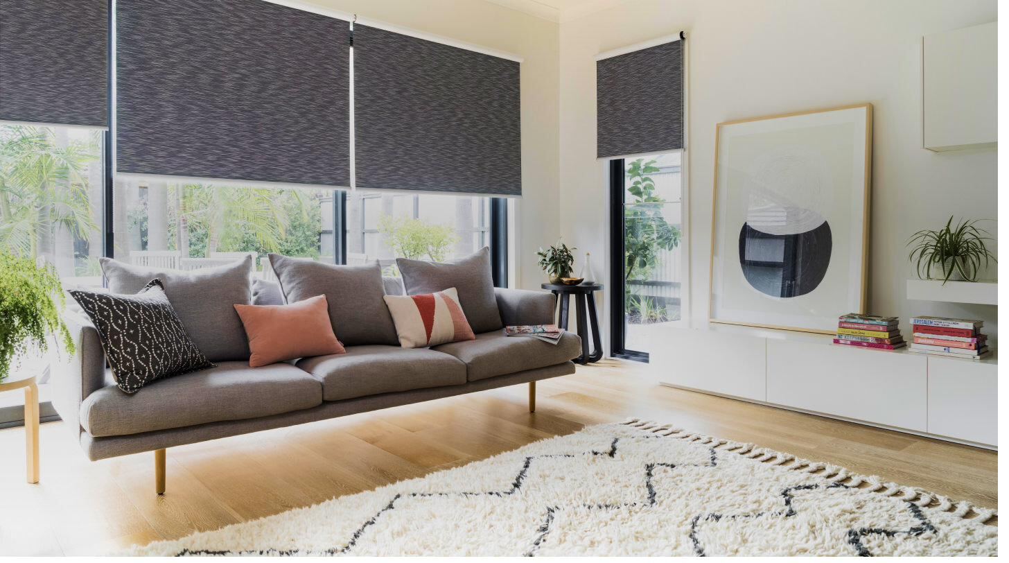 Charcoal grey roller blinds in a contemporary living room with oak floors and warm cushions — window blinds installation by Siddhi Decorators, Pitampura
